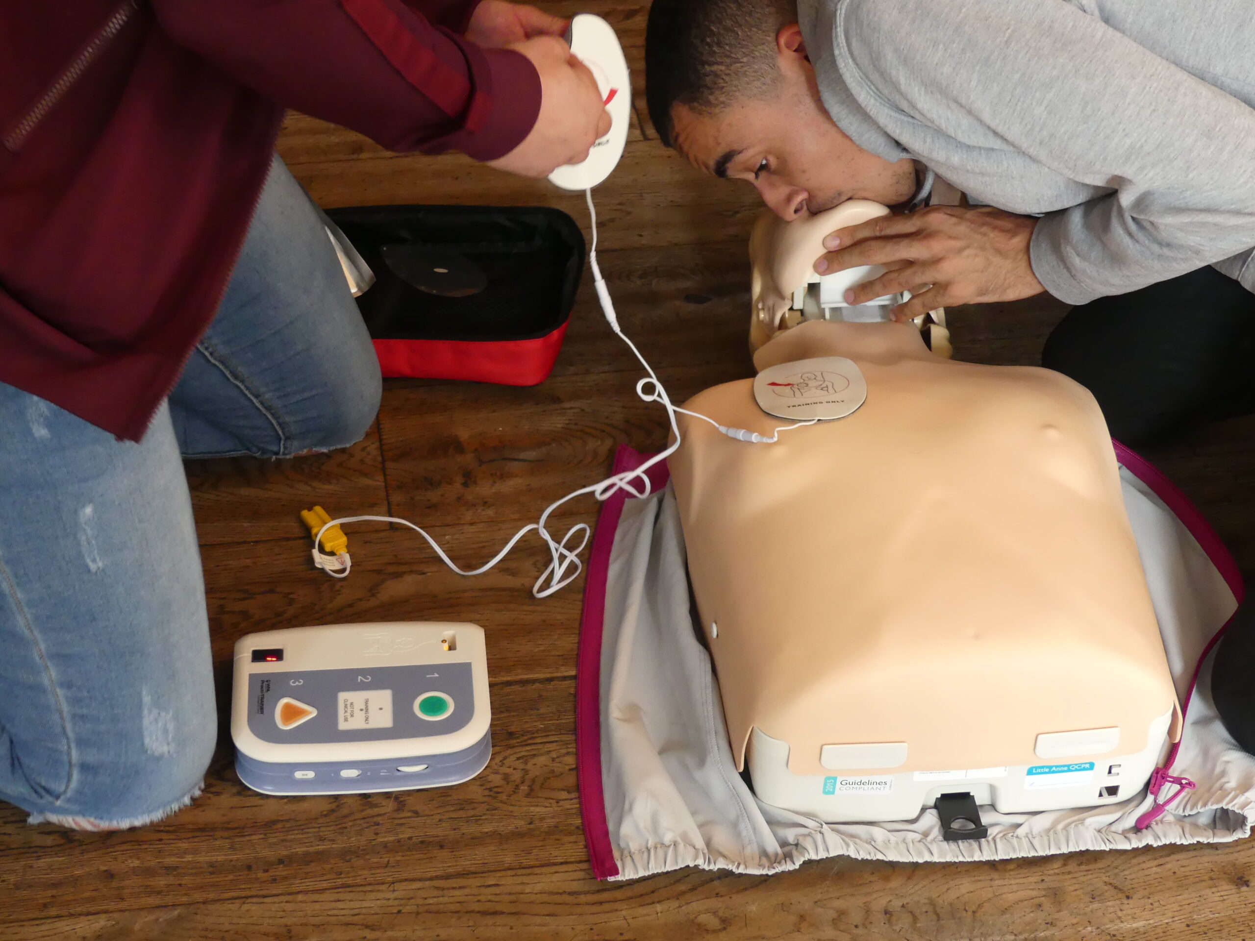 First aid training course with students practicing CPR and using a Defibrillator