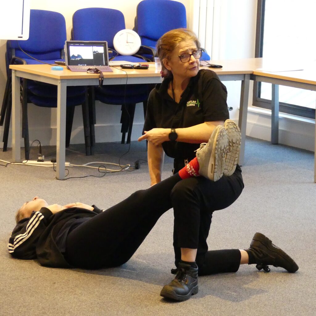 Trainer demonstrating effective shock positioning of laying down with legs elevated for a bleeding learner
